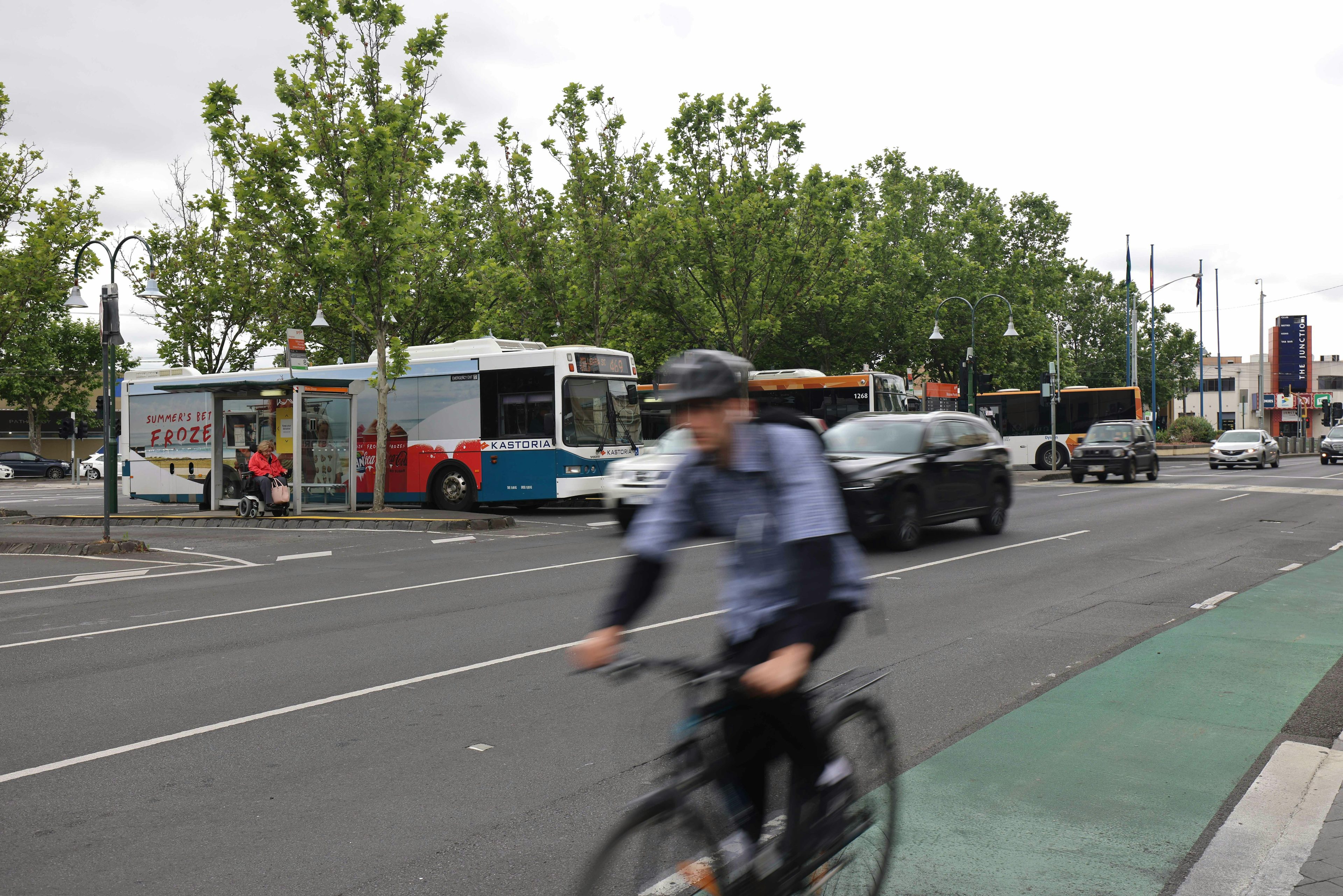 Street with cyclist on bike lane in foreground, cars and buses